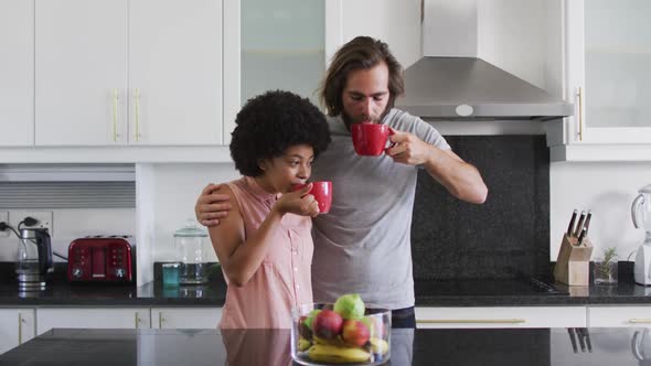 Mixed race couple drinking coffee together in the kitchen at home