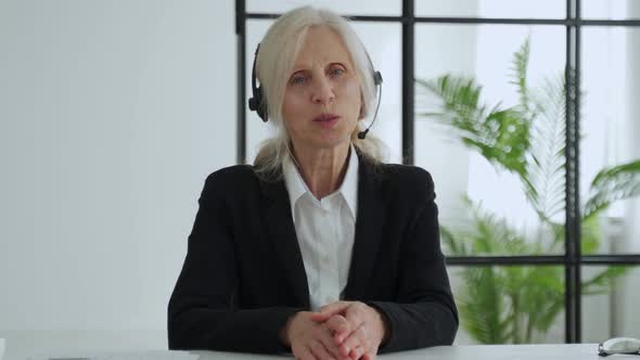 Elderly Whitehaired Woman Talks to a Camera Video Call Video Conference with Her Business Partners