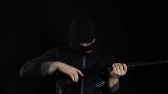 A Man in a Balaclava Mask Stands with an AK-47 Assault Rifle. The Bandit Charges the Machine and