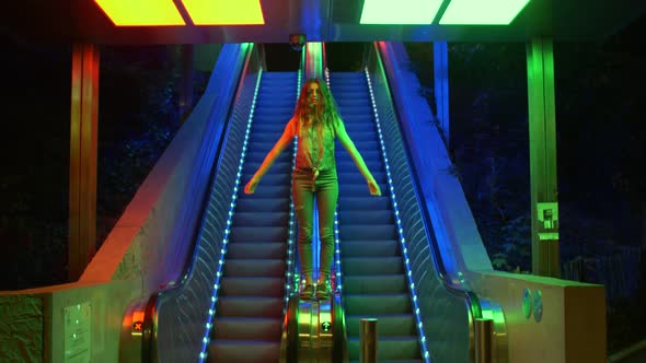 Young woman standing on an escalator with neon lights