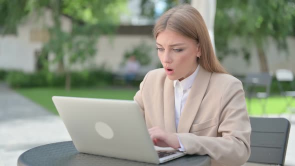 Young Businesswoman Feeling Shock While Using Laptop in Outdoor Cafe