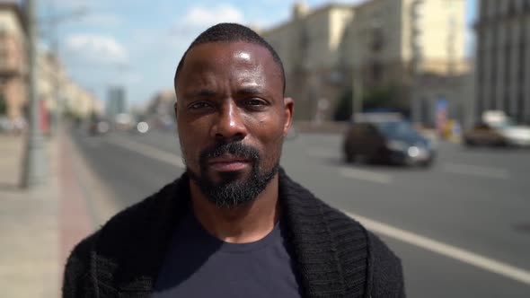 Portrait of an African Man in Dark Clothes and with a Beard. He Stands, Looks at the Camera and