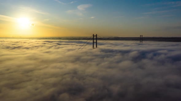 Aerial sliding hyper lapse of fog on the Humber passing over the Humber Bridge with the Sun in the s