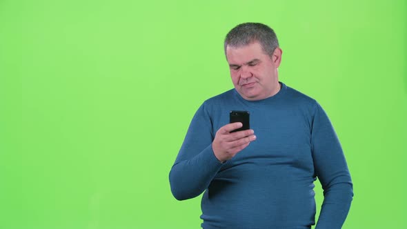 Adult Man Is Looking at the Phone for a Message. Green Screen