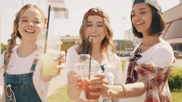 Positive models holding and drinking fresh cocktail smoothie outdoors