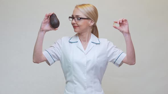 Nutritionist Doctor Holding Organic Avocado Fruit and Medicine or Vitamin or Omega 3 Capsule