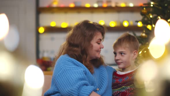 Portrait of Beautiful Smiling Mother and Son Hugging at Christmas Eve