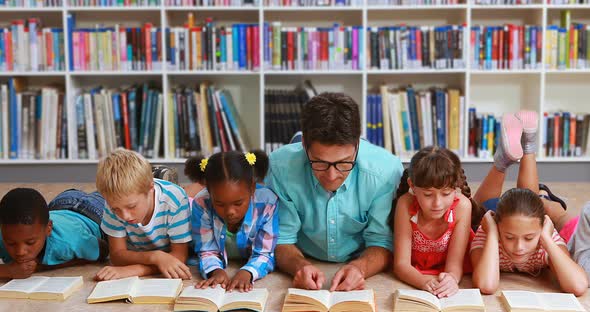 Teacher and Kids Lying on Floor Reading Book in Library