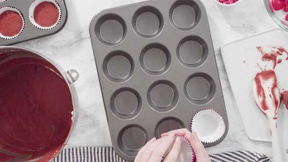 Flat lay. Step by step. Scooping cupcake batter into foil cupcake cups to bake red velvet cupcakes.