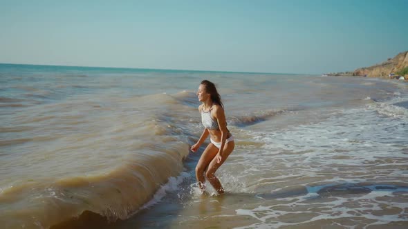 Happy Carefree Lauhging Slender Woman with Beautiful Fitbody at Seashore with Waves After Storm Girl