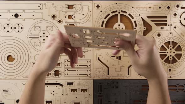 Hands Holding A Pre-Cut Mechanical Wooden Puzzle Toy. - Overhead Shot