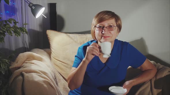 Happy Senior Woman Drinking Tea Sitting on the Chair