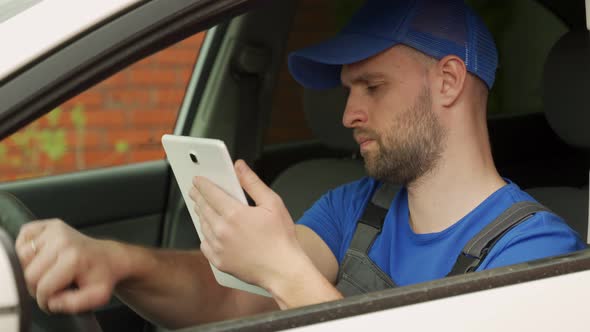 Man Sits on Driver Seat and Makes Notes About Car on Tablet