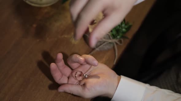 Groom in a White Shirt Drops Wedding Rings To the Palm of His Hand. Man Touches the Rings