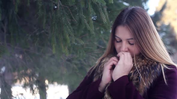 Beautiful Girl Warmes Her Hands with Her Mouth in the Winter Forest