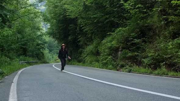 hipster woman bounces and throws her hat up on the road while traveling in countryside