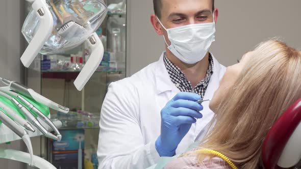Male Dentist Wearing Medical Mask Examining Teeth of Female Patient