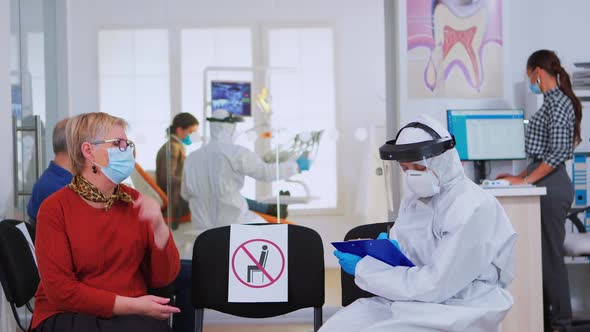 Dentist with Face Shield Talking with Elderly Woman Before Examination