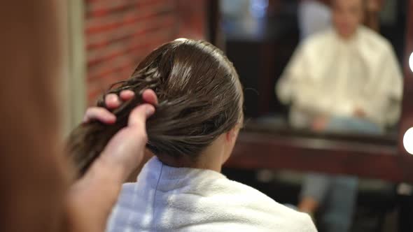 Closeup Unrecognizable Hairstylist Applying Hair Lotion on Long Brown Female Hair