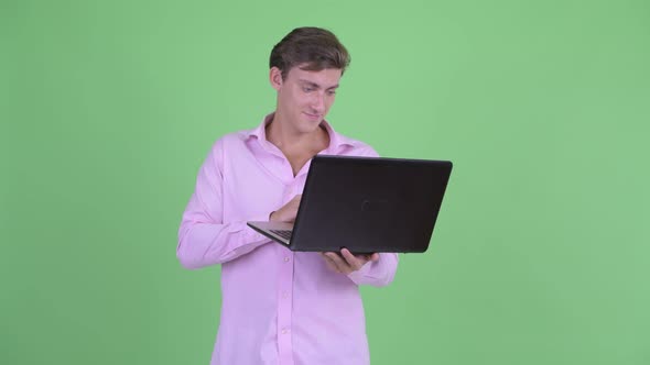 Happy Young Handsome Businessman Using Laptop