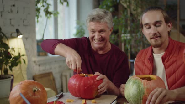 A Young Man and His Parents are Carving Pumpkins for Halloween Together