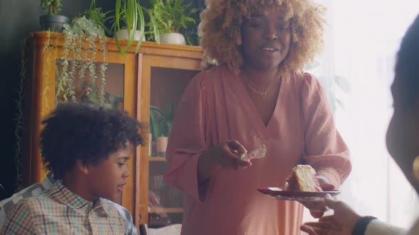 Happy Woman Putting Cake on Plates at Family Home Dinner