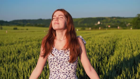 Ginger Woman with Freckles Enjoys Nature Inhales Full Chest of Air at Sunset