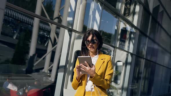 Young Businesswoman in a Suit is Working on Tablet Computer Near Modern Glass