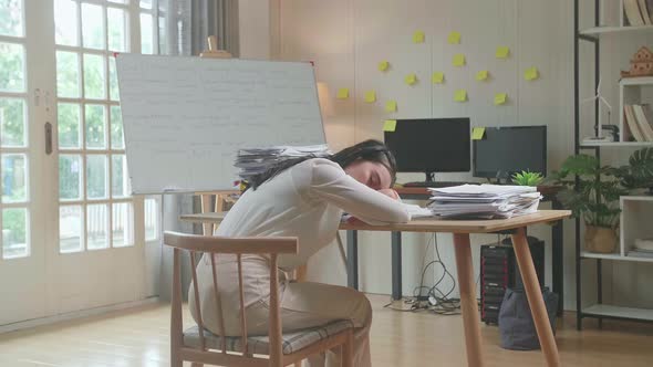 Back View Of Asian Woman Sleeping While Working Hard With Documents At The Office