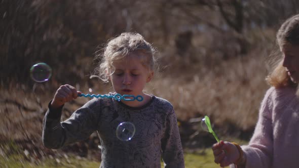 Brother And Sisters Blowing Bubbles From Bubble Wand