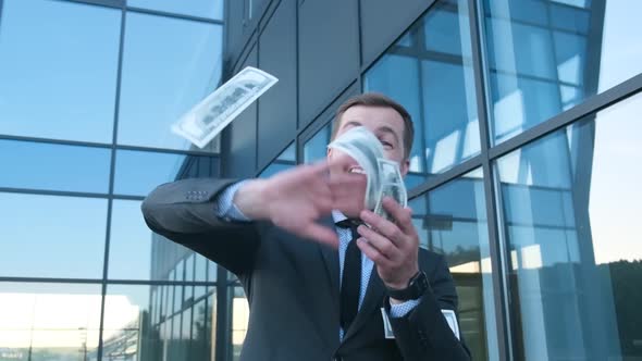 Businessman in Suit Throws Money Dollars at Camera Standing on the Street Near the Office Building