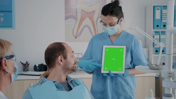 Assistant Vertically Holding Digital Tablet with Green Screen