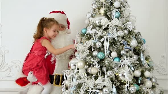 Santa Claus with Pretty Little Girl Decorating Christmas Tree