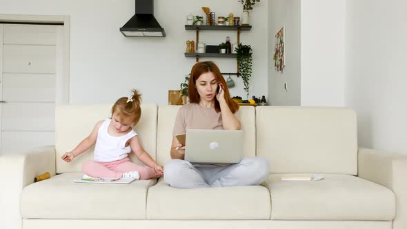 Mother Working From Home Having a Work Video Call Phone Call and Child Playing Nearby