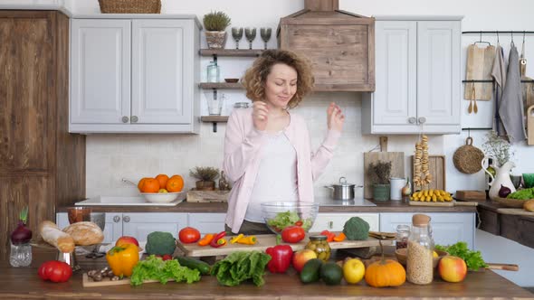 Happy Pregnant Woman On Kitchen Making Healthy Salad.