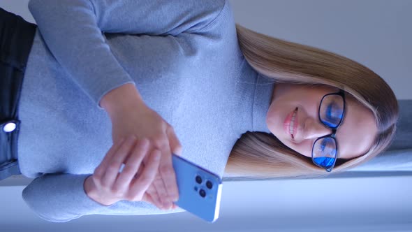 Vertical video of young blond female using new mobile phone in 4k video