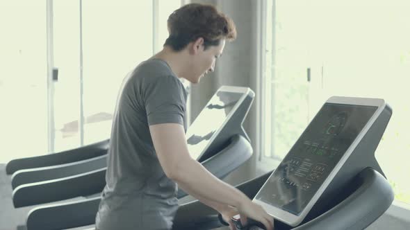 Asian young man exercise with running on treadmill in the gym.