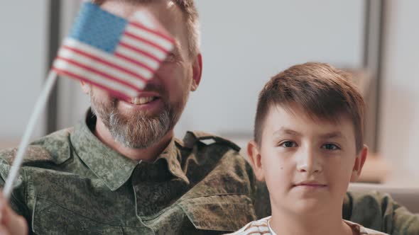 Portrait of Army Man and his Son Waving American Flags alt