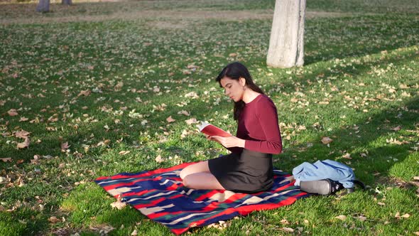 A young woman school girl reading a book on a campus lawn or outdoor park SLOW MOTION.