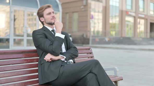 Pensive Businessman Thinking While Sitting Outdoor on Bench