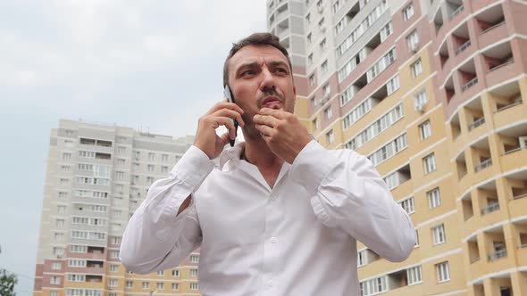 Distressed Frustrated Businessman in a White Shirt Speaks on the Phone