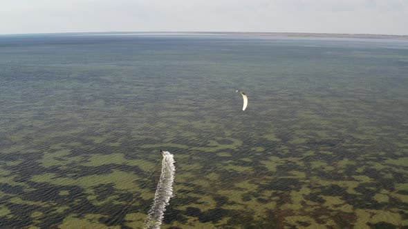 People go kitesurfing on the sea. The wind carries the athlete along the sea waves.