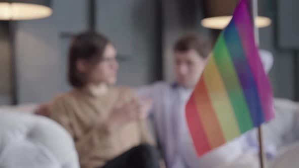 Focus Changes From Rainbow Lgbt Flag To Gay Couple Chatting at the Background. Portrait of Confident