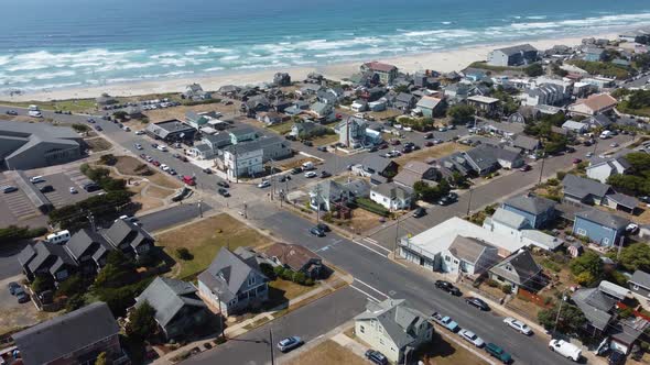 Drone shot of cars driving on the streets of a small coastal town in Oregon with the Pacific Ocean i