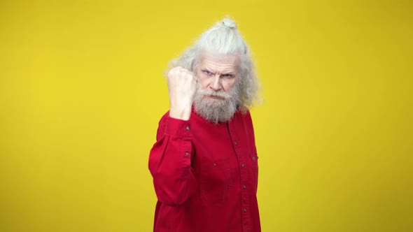 Angry Senior Bearded Man Threatening Camera with Clenched Fist