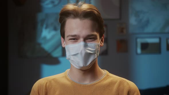 Portrait of Young Man with Light Blue Eyes Smiling Wearing Medical Protective Mask for Prevention