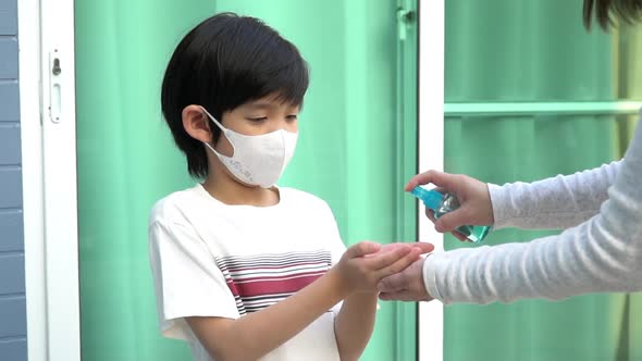 Asian Mother Spraying Sanitizer On Son Hands