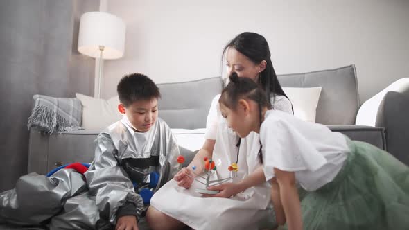 Asian Mother with Kids Play in the Living Room at Home a Boy in an Astronaut Costume Sitting on the