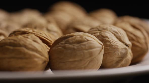 Cinematic, rotating shot of walnuts in their shells on a white surface - WALNUTS 