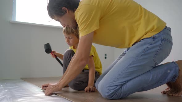 Father and His Little Son Install Laminate on the Floor in Their Apartment